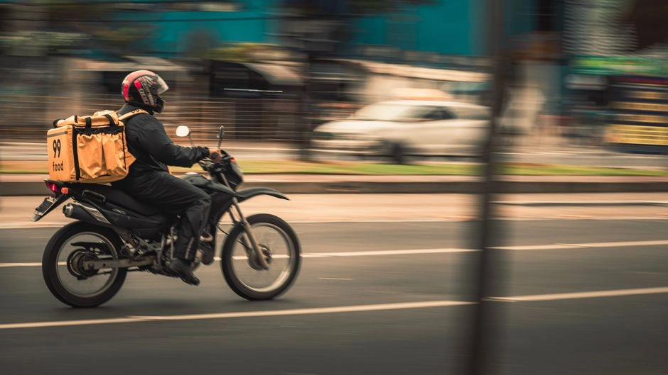 外送騎士騎車在街頭送餐，代表打工族常見的外送兼職工作