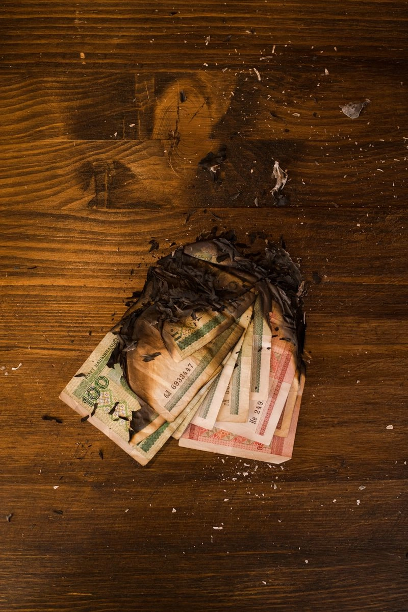 燒毀的鈔票堆放在桌面上，象徵地下錢莊造成的財務損失與風險