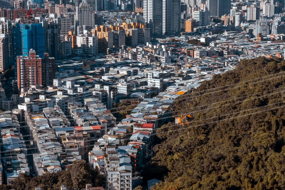 從山坡俯瞰台灣城市,密集的公寓與老式透天住宅一路延伸到遠方的高樓大廈,呈現換屋族面對的住宅市場